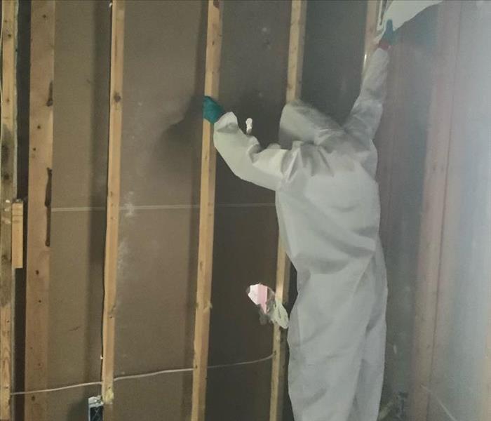 man in hazmat suit rips wall down during restoration