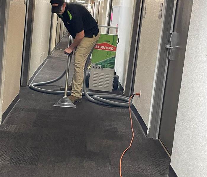SERVPRO employee using water extraction unit on carpet