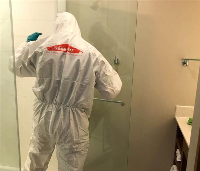 man in hazmat suit disinfects shower